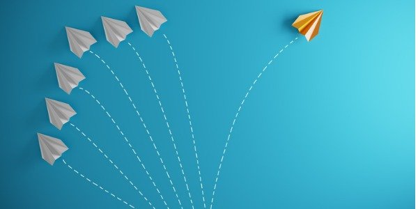 Group of paper airplane in one direction and with one individual pointing in the different way.