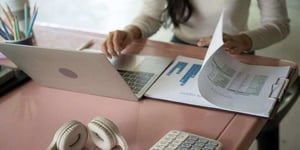 Woman checking business paperwork and typing information on laptop to researching data.